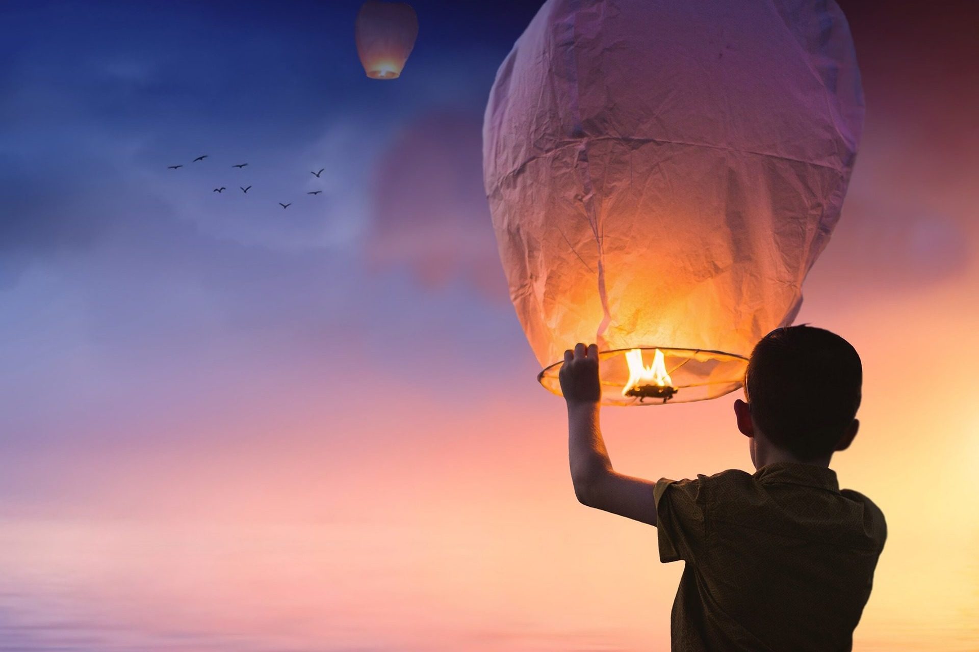 Einzelsession: Ein Kind lässt einen Papierballon steigen vor einem bunten Horizont